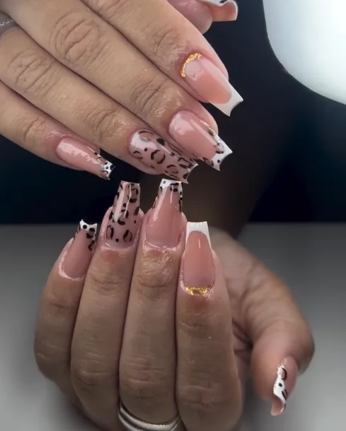 Unhas nude com desenhos escuros e pequenos detalhes dourados