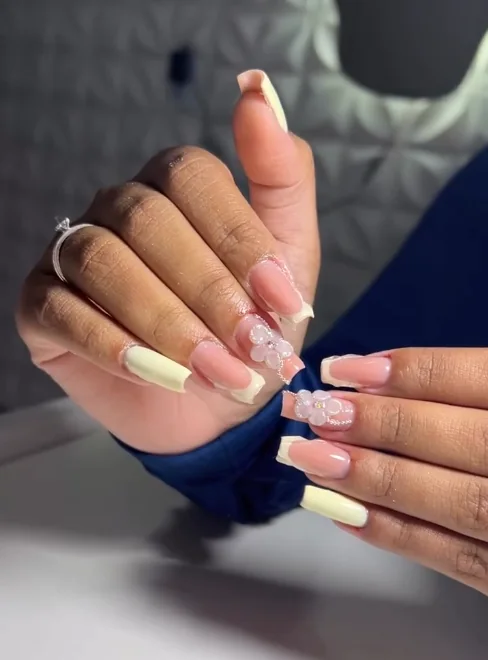 Unhas nude e claras com pequenas flores em relevo